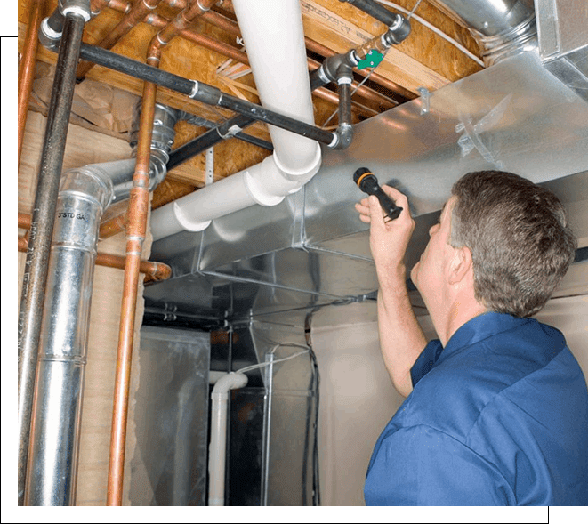 A man is inspecting pipes in an unfinished room.